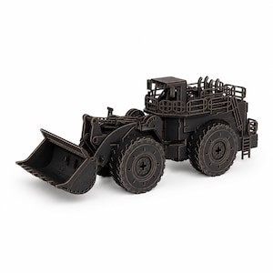 May include: A dark brown, laser-cut wooden model of a heavy-duty wheel loader construction vehicle. The model features intricate details including a large front bucket, four thick treaded wheels, a cabin with railings, and a rear ladder assembly.