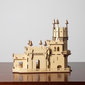 Pu&ograve; includere: Un modello di castello in legno con pi&ugrave; torri, merlature e porte ad arco. Il castello &egrave; costruito in legno chiaro con accenti pi&ugrave; scuri e poggia su una superficie di legno. Il modello ha un design dettagliato, che mostra una struttura architettonica in miniatura.
