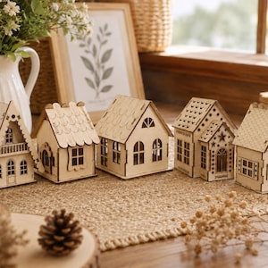 May include: Five miniature wooden houses, unpainted, with intricate architectural features. Each has cut-out windows and doors, and different roof styles. They are displayed on a natural fibre mat, suggesting a craft or decorative purpose. The houses are approximately 10-15 cm in height.
