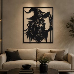 May include: A black metal wall art piece featuring a silhouette of a figure wearing a wide-brimmed pointed hat and holding a staff. The design is enclosed within a rectangular frame, showcasing intricate cut-out details of the character's attire.