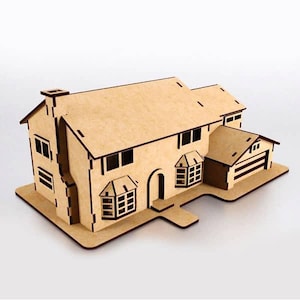 Puede incluir: Maqueta de madera cortada con láser de una casa con garaje. El modelo presenta una casa de dos pisos con chimenea, múltiples ventanas y una puerta principal. El garaje está adjunto al lado de la casa. El modelo es de madera clara.