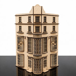 Op de afbeelding: Een lasergesneden houten model van een hoekgebouw met een bakstenen gevel, meerdere rechthoekige ramen en een centrale gebogen erker. Twee uithangborden met de letters W en B zijn aan de buitenmuren bevestigd.