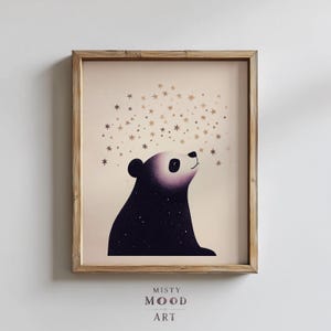 May include: A framed art print featuring a stylized bear looking up at a cluster of gold stars. The bear is primarily dark purple with a light purple face and a white eye. The print is labeled "Misty Mood Art". The frame is made of light brown wood.