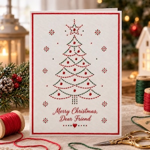 Puede incluir: Una tarjeta de felicitación rectangular blanca con un borde rojo presenta un diseño de árbol de Navidad bordado con hilo verde y rojo. El árbol está coronado con una estrella y decorado con cuentas rojas. El texto dice Merry Christmas, Dear Friend.