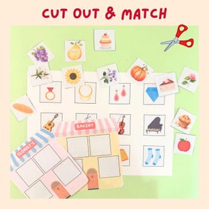 May include: A children's matching game with the text "CUT OUT & MATCH". The game features illustrated cards of objects such as a cupcake, pear, and ring, alongside matching shop cards for a bakery and florist. A pair of scissors is also included.