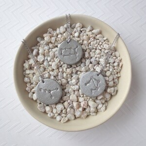 May include: Three silver necklaces with zodiac constellation pendants on a white background. The pendants are in the shape of circles with the constellations of Gemini, Libra, and Cancer.