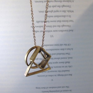 Peut inclure: Un collier en or avec un pendentif géométrique composé d'un cercle, d'un carré et d'un triangle.