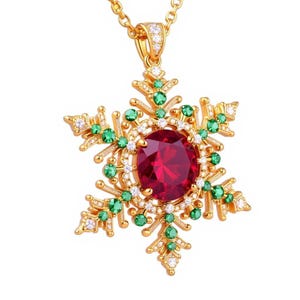 Könnte beinhalten: Eine goldfarbene Schneeflocken-Anhänger-Halskette mit einem großen, runden, roten Edelstein in der Mitte. Das Schneeflocken-Design ist mit grünen und weißen Edelsteinen verziert. Ein festliches Accessoire.