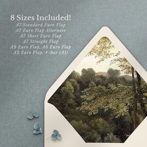 May include: A white envelope with a window showing a painting of a forest scene. The envelope is on a blue textured surface with a small ring box and a few blue flowers.