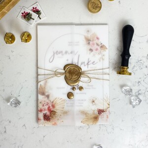 May include: A wedding invitation with a watercolor floral design and a wax seal with a leaf design. The invitation is printed on translucent paper and has a rustic, bohemian feel.