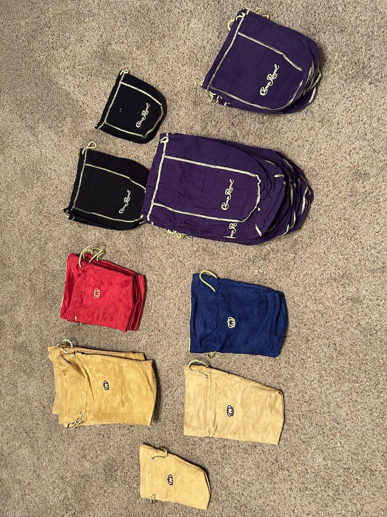 Puede incluir: Una colecci&oacute;n de bolsas de cord&oacute;n en varios colores, incluyendo rojo, azul, morado y beige. Algunas bolsas tienen el texto "Crown Royal" y un logotipo de corona.