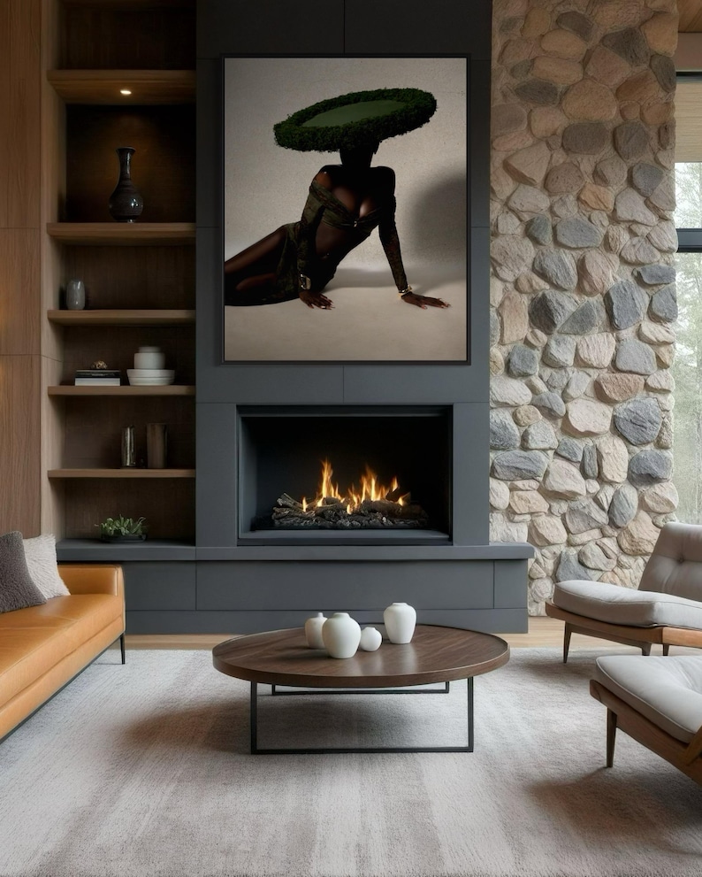 May include: A modern living room with a large framed artwork above a fireplace. The artwork features a person wearing a green hat. The room includes a brown leather sofa, a round coffee table, and two armchairs.