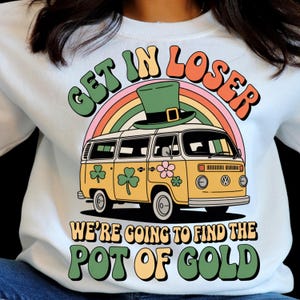 May include: White sweatshirt with a retro graphic featuring a yellow van, rainbow, and a green leprechaun hat. Text reads "GET IN LOSER" and "WE'RE GOING TO FIND THE POT OF GOLD". The design includes shamrocks and flowers, perfect for St. Patrick's Day.