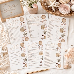 Może przedstawiać: Zestaw pięciu białych kart do gier na baby shower z napisem Sea You Soon, ozdobionych ilustracjami muszli i rozgwiazd w odcieniach beżu i brązu. Karty zawierają tytuły takie jak Wishes for Baby, What's in Your Beach Bag oraz Baby Trivia.