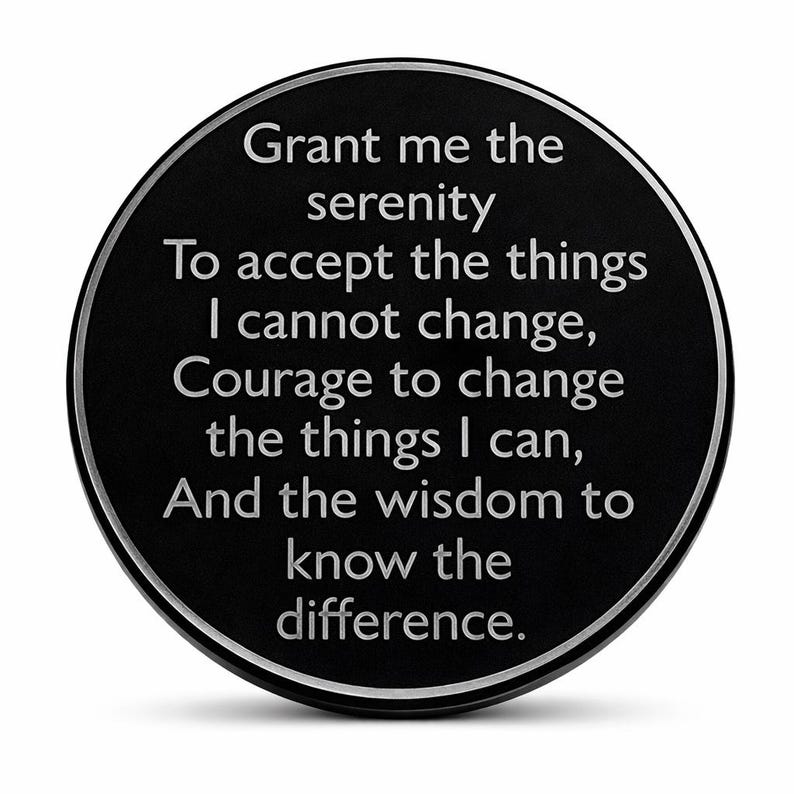 May include: A black, round token with a silver border. The text "Grant me the serenity to accept the things I cannot change, Courage to change the things I can, And the wisdom to know the difference" is inscribed in silver lettering.