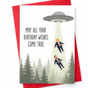 May include: A white birthday greeting card featuring a gray UFO hovering over a forest of green pine trees. A beam of light shines down, lifting two figures in dark suits and red ties. The text reads, MAY ALL YOUR BIRTHDAY WISHES COME TRUE.