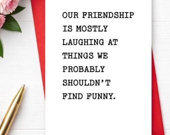 May include: A white rectangular greeting card with black typewriter-style text that reads: OUR FRIENDSHIP IS MOSTLY LAUGHING AT THINGS WE PROBABLY SHOULDN'T FIND FUNNY. The card is positioned on a red envelope, accompanied by a gold pen.
