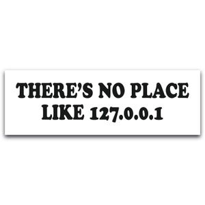 May include: A white rectangular sticker featuring the text "THERE'S NO PLACE LIKE 127.0.0.1" in bold, black font. The phrase is centrally aligned, creating a simple and modern aesthetic.