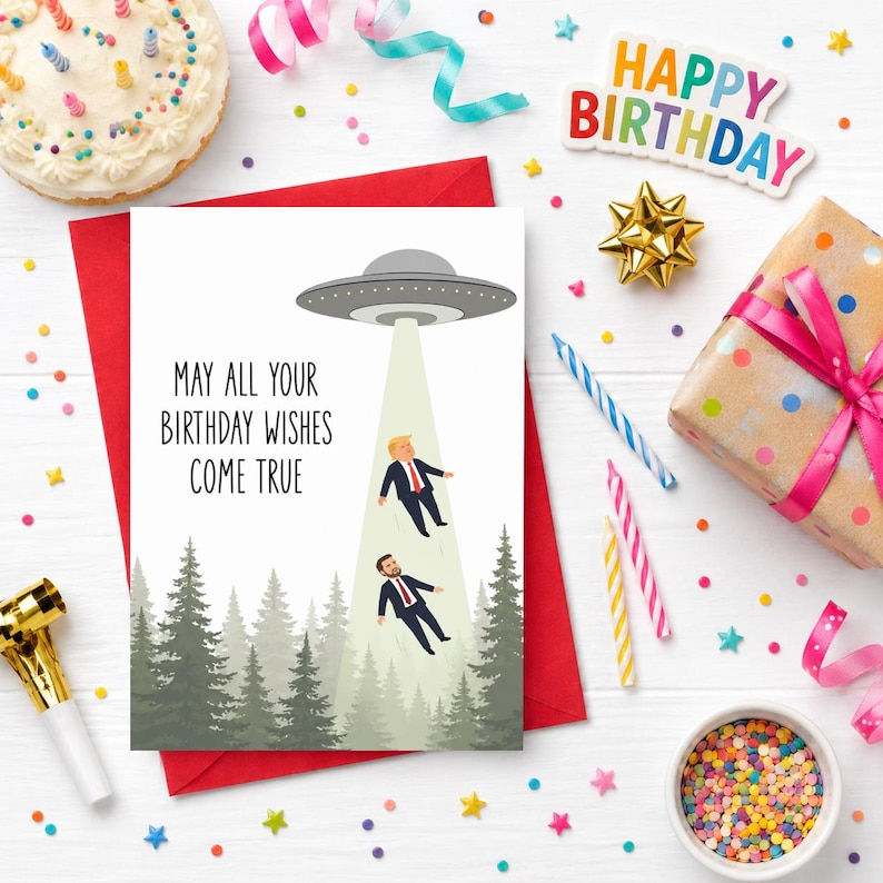 May include: A rectangular birthday greeting card featuring a gray UFO hovering over a forest, beaming down two figures in suits. The text reads, "MAY ALL YOUR BIRTHDAY WISHES COME TRUE." The card is set against a white background with confetti.