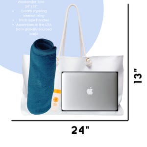 May include: White weekender tote bag, 24 inches wide and 13 inches tall, with cream sheeting interior lining and thick rope handles. The bag contains a laptop, a rolled blue towel, and a bottle of sunscreen.