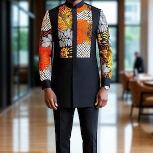 May include: A black suit with a mandarin collar, featuring a vibrant patterned panel on the chest and sleeves. The pattern incorporates orange, yellow, and white floral and geometric designs. The suit is paired with black trousers.