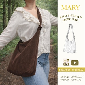 May include: A brown suede hobo bag with a knot strap, worn over the shoulder. The bag is a triangular shape. The image also includes the text "MARY KNOT STRAP HOBO BAG", "Beginner Friendly", and "INSTANT DOWNLOAD +VIDEO TUTORIAL".