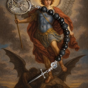 May include: A rosary with black lava stone beads and a silver-toned crucifix. The rosary is set against a backdrop of a painting depicting an angel with wings and a sword, and a defeated demon.
