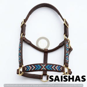 May include: A brown leather horse halter featuring brass hardware and decorative beadwork in geometric patterns of turquoise, blue, red, and white. The halter includes adjustable straps and metal rings, with the text SAISHAS visible at the bottom.