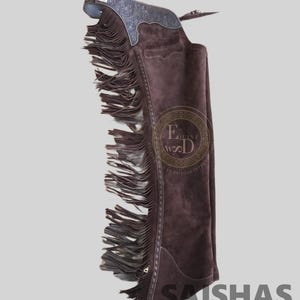 May include: A dark brown suede leather chaps piece featuring long fringe along the side, an embossed floral pattern on the upper yoke, and a buckle closure at the top. The text Equine WD and SAISHAS is visible on the surface of the brown leather.