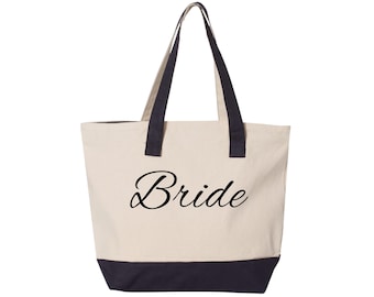 Könnte beinhalten: Eine Tragetasche aus Segeltuch mit schwarzen Griffen und einem schwarzen Boden. Das Wort "Bride" ist in einer kursiven Schriftart auf die Vorderseite der Tasche gedruckt. Die Tasche hat eine natürliche Farbe.