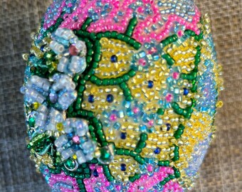 May include: A beaded Easter egg with a floral design in shades of blue, pink, green and yellow.