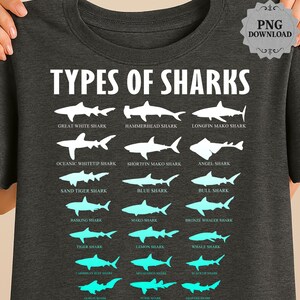 May include: Dark gray t-shirt featuring a white graphic with the text "TYPES OF SHARKS" above illustrations of various shark species. The shirt displays shark silhouettes with their names, including Great White, Hammerhead, and Tiger Sharks.