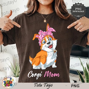 Puede incluir: Camiseta marrón con un corgi de dibujos animados que lleva una diadema rosa con lunares. El corgi tiene pelaje naranja y blanco y una expresión feliz. El texto "Corgi Mom" está debajo del corgi. La marca "Totu Tayo" está en la parte inferior.