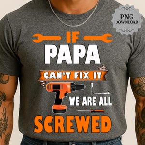 May include: A grey t-shirt featuring the text "IF PAPA CAN'T FIX IT WE ARE ALL SCREWED." The design incorporates orange spanners, a drill, and the word "SCREWED" in orange. This is a casual wear item.