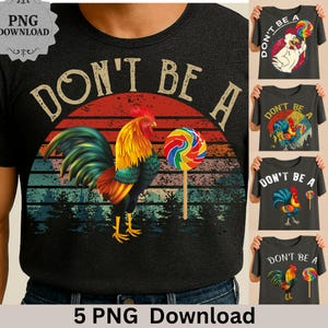 May include: A black t-shirt featuring a colorful rooster graphic with the text "DON'T BE A" above it. The rooster is holding a lollipop. Additional shirts with similar designs are displayed.