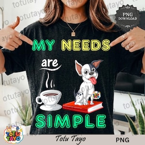 May include: Black t-shirt with the text "MY NEEDS are SIMPLE" in green and yellow. A cartoon dog sits on a red book next to a coffee cup. The shirt has a distressed look.
