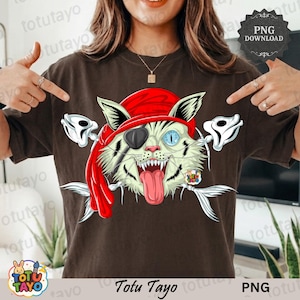 Pode incluir: Camiseta marrom com um desenho de gato pirata. O gato usa uma bandana vermelha e tapa-olho, com detalhes de espinhas de peixe. A língua do gato está de fora. Os textos "Totu Tayo" e "PNG" são visíveis.