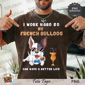 Op de afbeelding: Bruin t-shirt met de tekst "I WORK HARD SO MY FRENCH BULLDOG CAN HAVE A BETTER LIFE." Het ontwerp toont een cartoon Franse Bulldog met zonnebril en een cocktail. Het t-shirt heeft een PNG download tag.