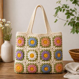 May include: A rectangular crochet tote bag featuring a grid of twelve granny squares. Each square displays a multi-colored flower motif with a yellow center and petals in shades of pink, blue, purple, orange, and white, joined by cream yarn.