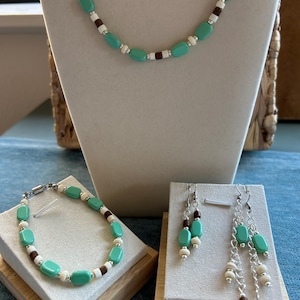 May include: A white ceramic mug with a black handle and the text "But First, Coffee" in a handwritten style. The mug is on a white surface. The mug is approximately 4 inches tall.