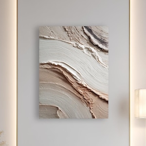 May include: An abstract textured wall art piece with a neutral color palette of beige, white, and brown hangs on a white wall. The artwork is the focal point of a modern, minimalist interior. A gold floor lamp and a decorative vase with dried plants are also visible.