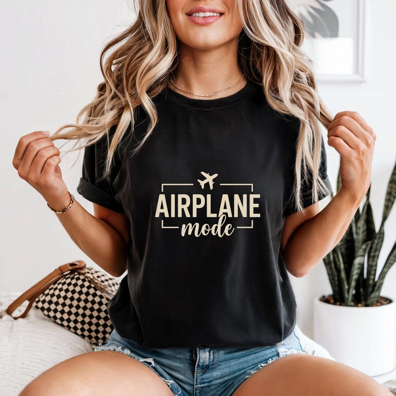 May include: Black t-shirt with the text "AIRPLANE mode" in a rectangular design, featuring a small airplane icon. The shirt is a dark color and has rolled-up sleeves.