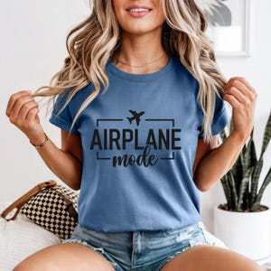 May include: A blue t-shirt with the words "AIRPLANE mode" in black, with a small airplane graphic above the word "AIRPLANE". The shirt is short-sleeved and made of a soft material.