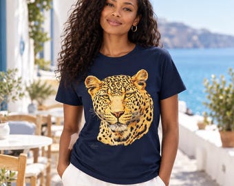Op de afbeelding: Een marineblauw t-shirt met korte mouwen en een grote, gedetailleerde grafische print van een luipaardkop in tinten geel, goud en zwart. Het t-shirt heeft een ronde hals en wordt gedragen met een witte broek.