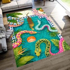 Op de afbeelding: Een rechthoekig vloerkleed met een zwembadscène-ontwerp. Het kleed heeft een turquoise zwembad met kleurrijke slangen, een luipaard en een menselijk gezicht. De rand heeft een blauw-wit tegelpatroon, met tropische planten.