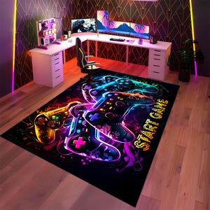 Könnte beinhalten: Ein schwarzer rechteckiger Gaming-Teppich mit einem Neon-Design von zwei sich überlappenden Gamecontrollern. Die Controller sind in leuchtenden Farben wie Gelb, Blau und Lila umrandet. Die Worte "START GAME" sind in Neon geschrieben. Der Teppich befindet sich in einem Spielzimmer.