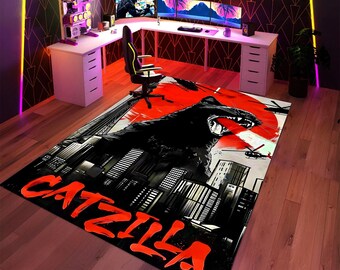 May include: A large rectangular rug featuring a black panther illustration with a red sun backdrop and city skyline. The rug has the word "CATZILLA" in large orange letters. The rug is in a gaming room with a white desk and multiple monitors.