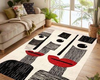 May include: A cream-coloured area rug with a striking abstract design of two faces. Each face has black and grey features, large black eyes, and bright red lips. The rug is placed on a wooden floor.