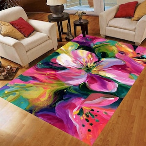 May include: A rectangular rug with a bold floral pattern. The rug displays large, abstract flowers in pink, purple, yellow, and green hues against a dark backdrop. It is positioned on a wooden floor.
