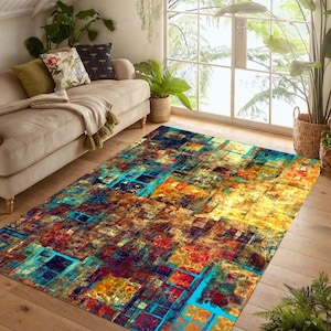 Puede incluir: Una alfombra rectangular con un diseño abstracto. La alfombra presenta una mezcla de colores, incluyendo azul, amarillo, rojo y marrón, creando un patrón geométrico. La alfombra está colocada sobre un suelo de madera, añadiendo calidez a la habitación.